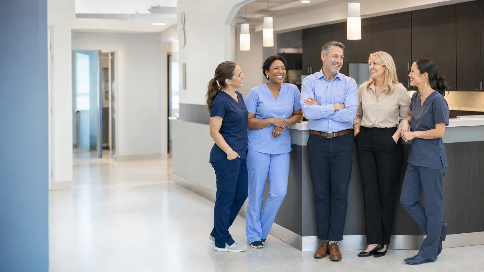 Medical practice staff and leadership smiling together near the reception area of a bright clinic