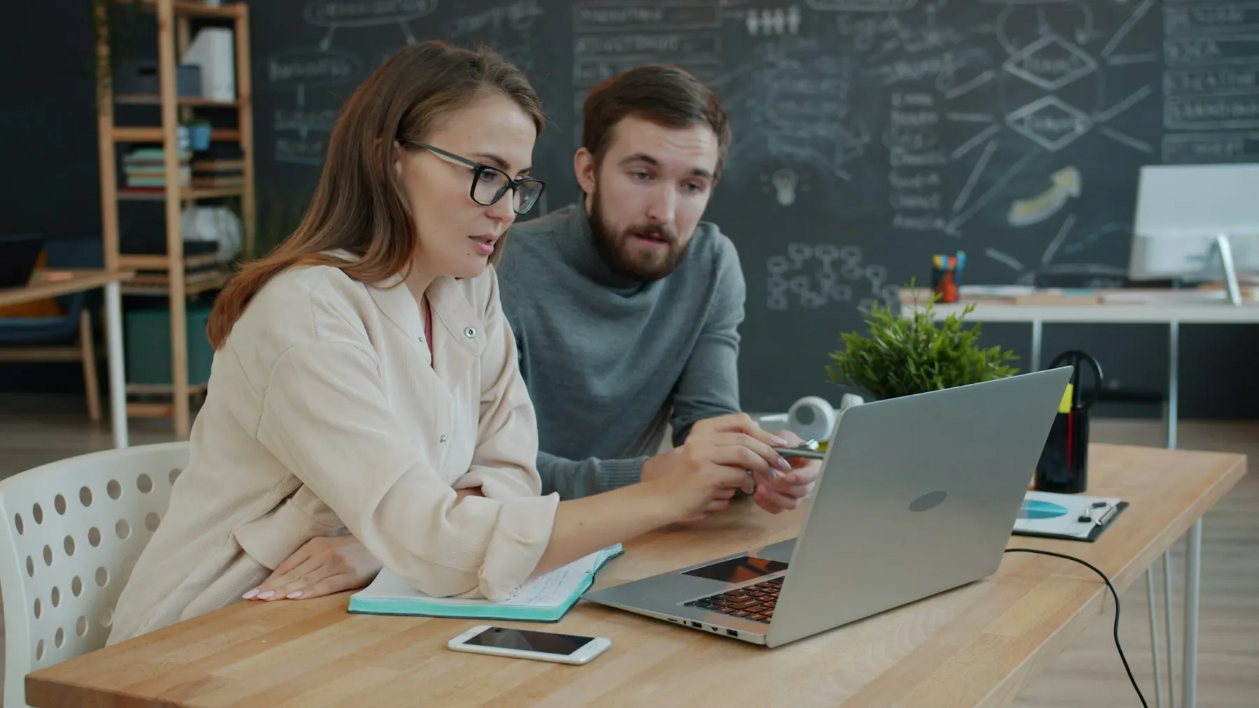 Internal IT professional and outside technology specialist collaborating together at a laptop